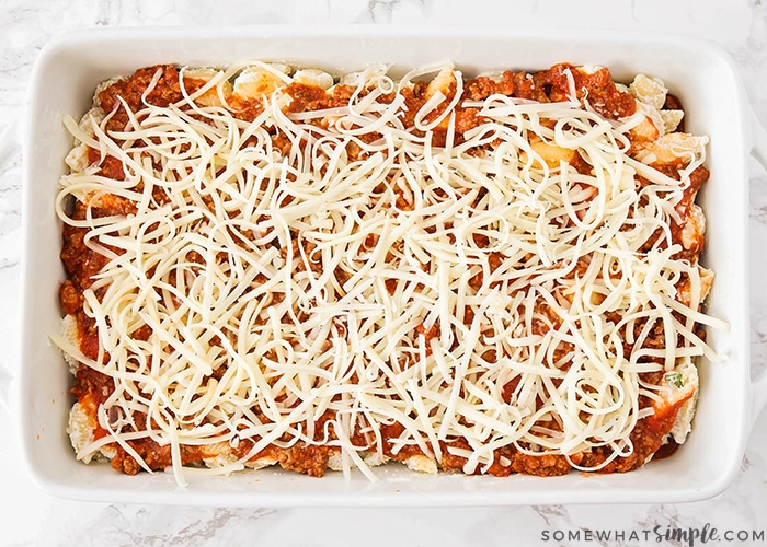 a pan of uncooked unstuffed shells topped with grated mozzarella cheese