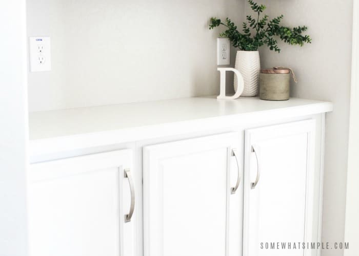 a white linen closet with chrome handles in the hallway of a house. 