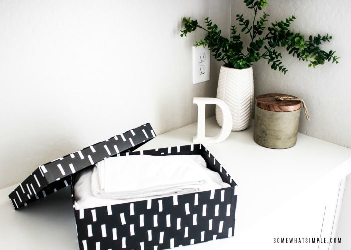 a black box sitting on a white counter with the lid off to the side and inside the box are neatly folded sheets