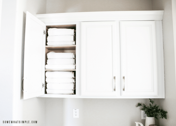 one door of a cupboard is open showing three levels of neatly folded white towels