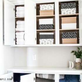 the doors of an organized white linen closet that are open revealing neatly stacked boxes and folded blankets