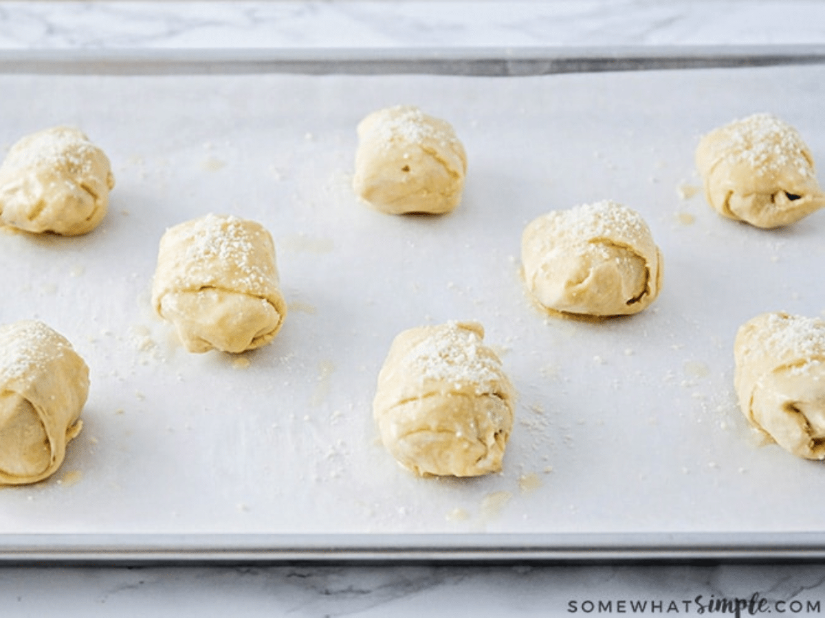 raw pizza rolls on a baking sheet.