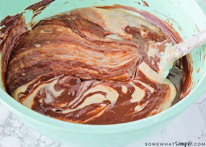 a mixing bowl with chocolate being mixed in with the ingredients to make banana bread