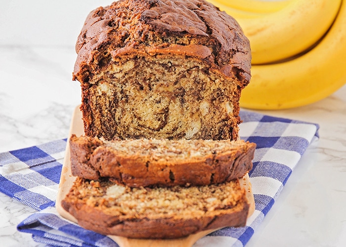 a loaf of chocolate banana bread on a counter with two slices cut off the end and laying on the counter showing a beautiful marbled coloring