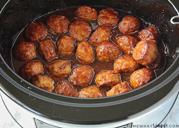 crock pot full of meatballs cooking in bbq sauce and grape jelly