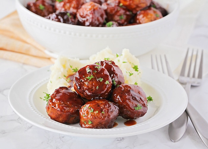 grape jelly meatballs on a plate with a side of mashed potatoes are an easy super bowl food