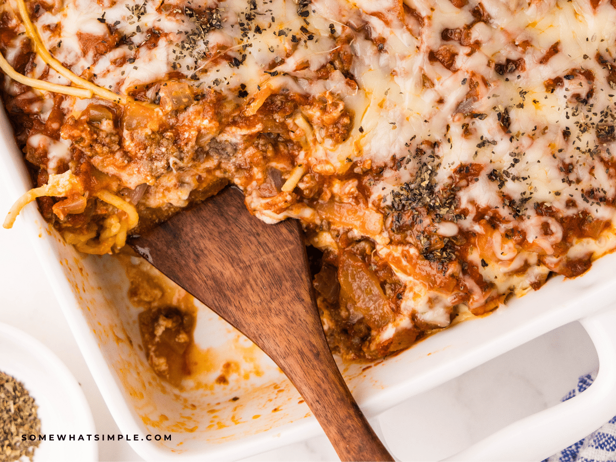 wood serving spoon in a dish of Baked Spaghetti