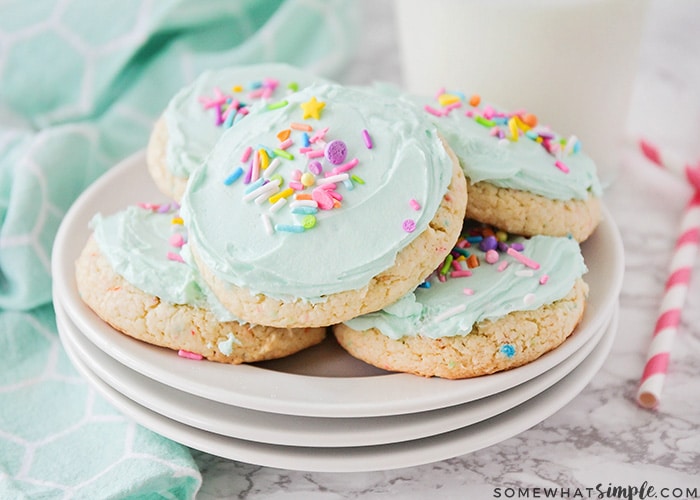 white cake mix cookies topped with a light green frosting and pastel colored sprinkles