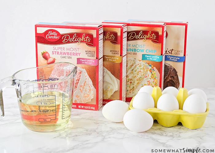 four boxes of different cake mixes on a counter next to oil and eggs