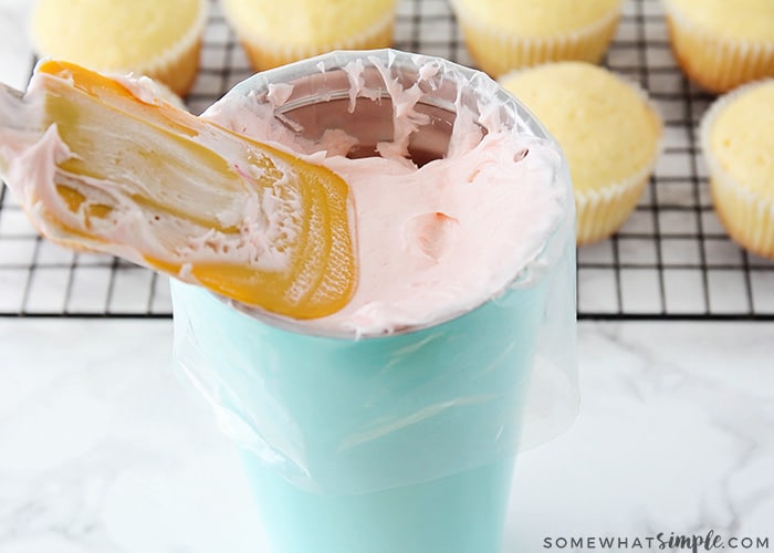 a cup lined with a piping bag filled with frosting