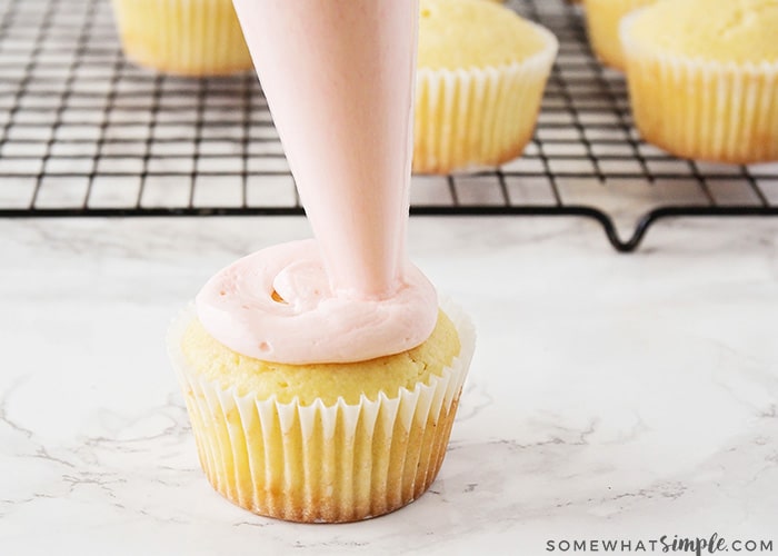 piping frosting onto a cupcake