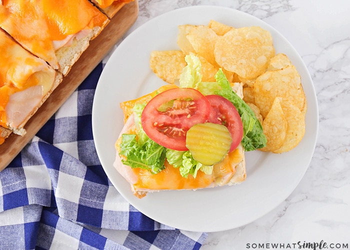 an open faced baked sandwiches on a plate with potato chips is a simple snack to serve during the super bowl