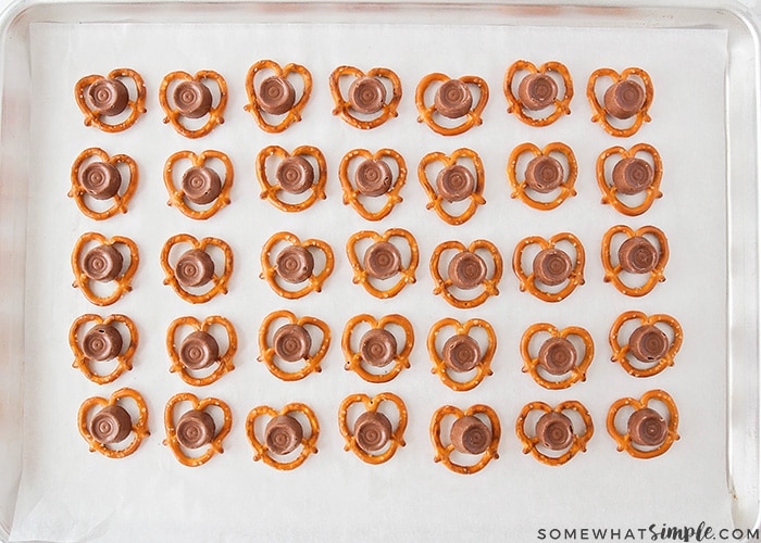 making chocolate pretzel turtles by placing a rolo on top of each pretzel 