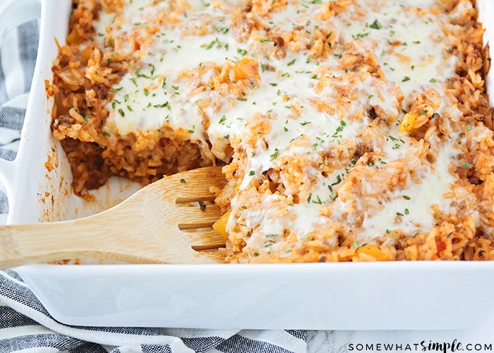 a pan of this easy stuffed bell pepper casserole with a corner cut out and a wooden spoon in its place