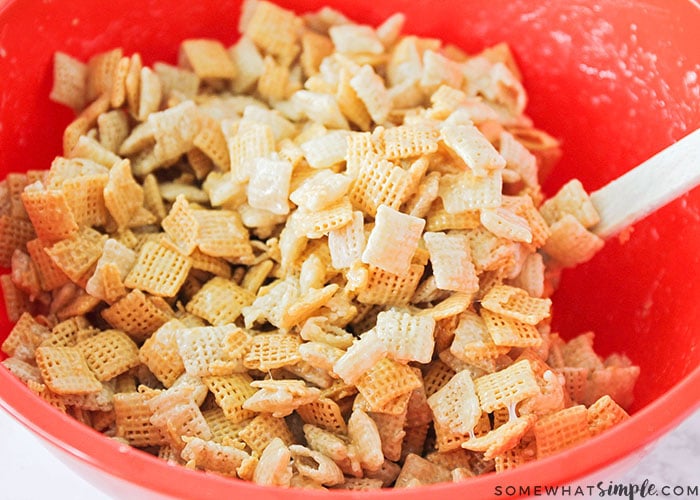 a red bowl being mixed with all of the ingredients for a sweet chex mix recipe