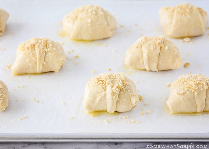 a baking sheet filled with chicken crescent rolls and topped with bread crumbs. The rolls are ready have not been cooked and are ready to go in the oven. 