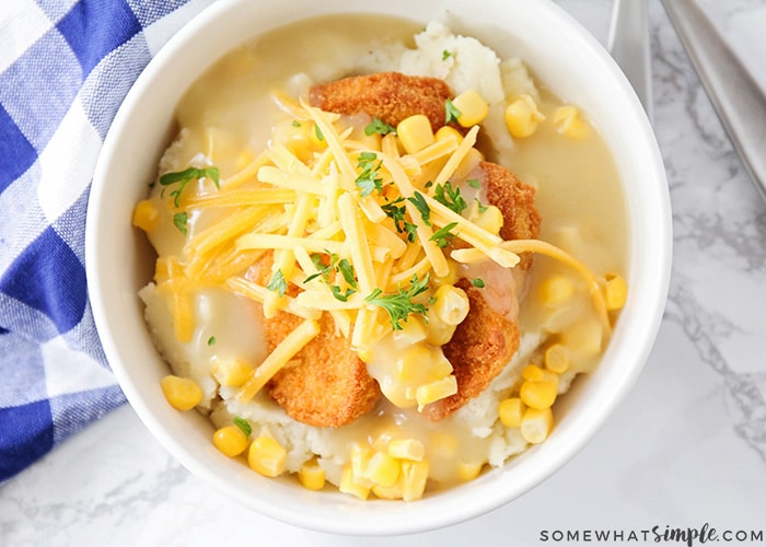 looking down on a bowl of KFC Mashed Potato Bowl Copycat topped with cheese, parsley and corn