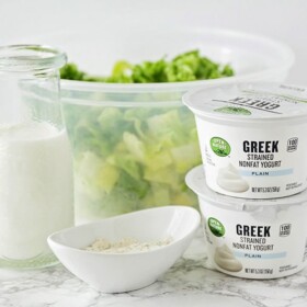 a jar of homemade ranch dressing that's next to a tub of Greek yogurt and a bowl of lettuce