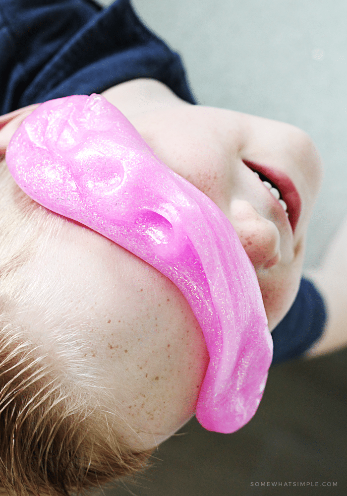 A young boy playing with homemade slime and putting it on his face. Learn how to make this easy slime recipe using just three simple ingredients.