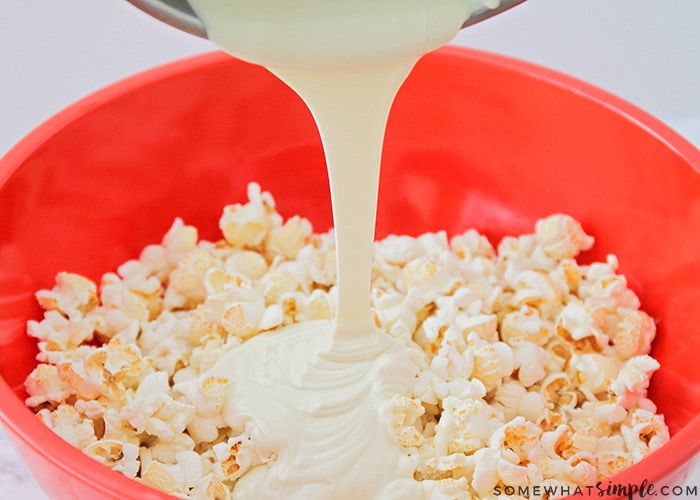 melted white chocolate being poured over popcorn