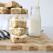 a stack of banana bars topped with cream cheese frosting and sliced bananas