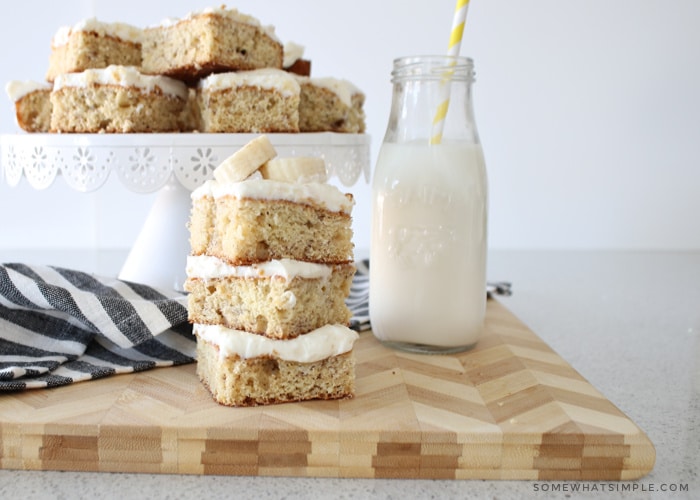 a stack of banana bars topped with cream cheese frosting and sliced bananas