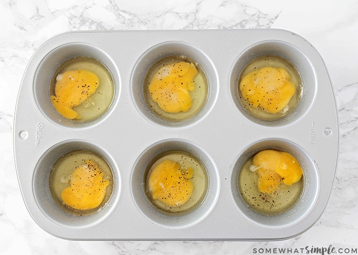 looking down on a jumbo baking tin with each ramekin filled with a cracked egg and sprinkled over the top.