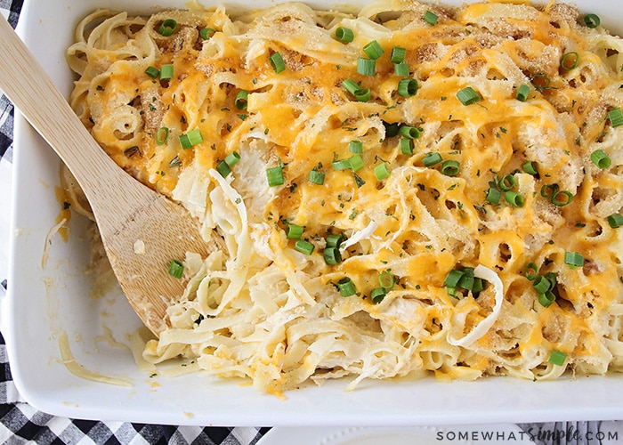 a dish of chicken tetrazzini with a wooden spoon in the corner of the baking pan where a scoop has recently been served.