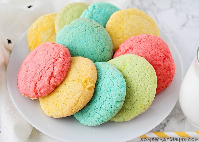 a white plate full of brightly colored jello cookies made with this simple recipe. The plate is full of red, blue, green and yellow jello cookies.