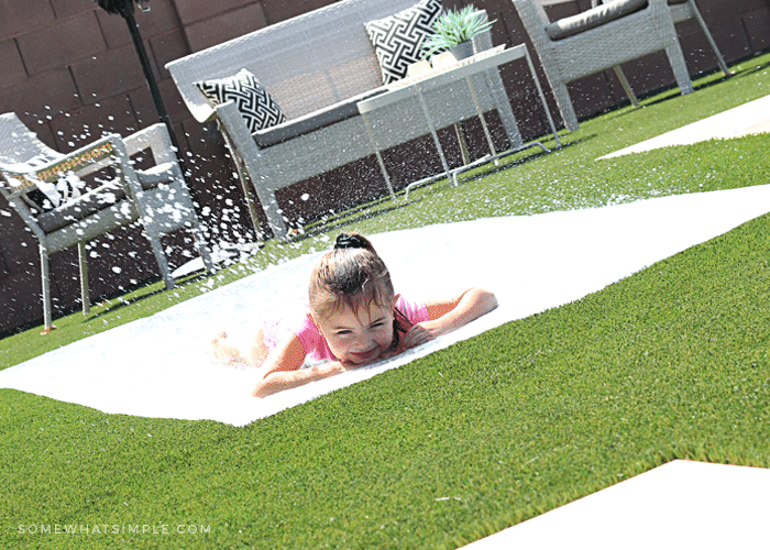 a little girl sliding on a homemade slip and slide