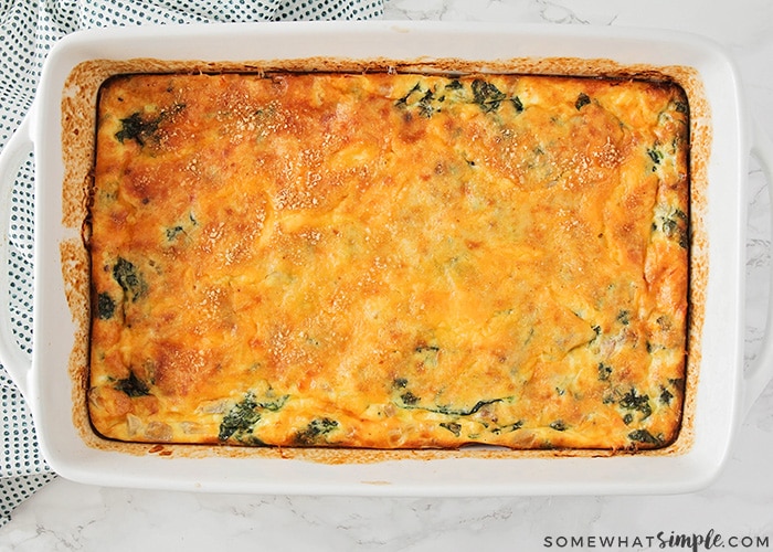 looking down on a baked breakfast casserole made with eggs and pieces of spinach can been seen on the top