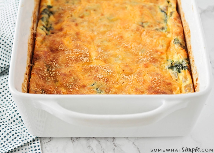 a baked egg and spinach casserole that just came out of the oven and the cheese on top is a golden brown color.