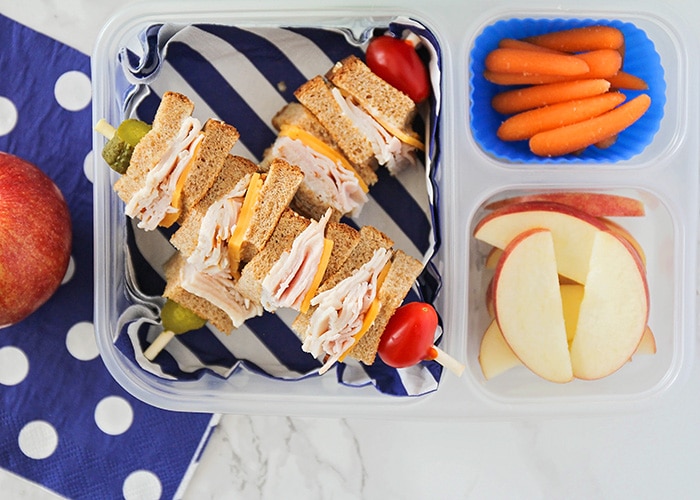 a lunch box with a sandwich, carrots and apple slices