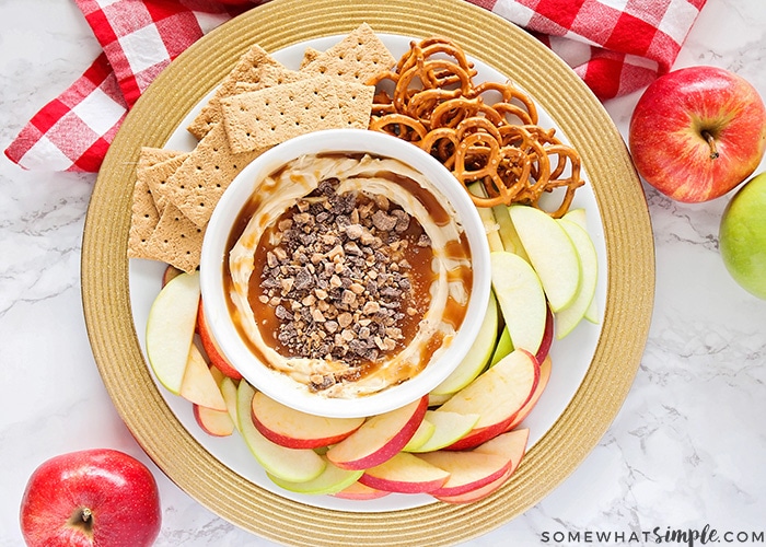 looking down on a bowl of caramel dip made with cream cheese surrounded by apple slices, graham crackers and pretzels on a serving dish