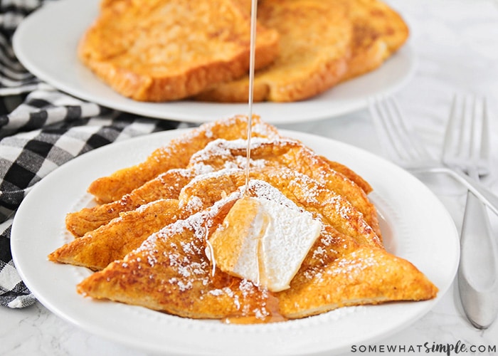 four slices of pumpkin french toast on a plate topped with a pad of butter and syrup being drizzled over the top