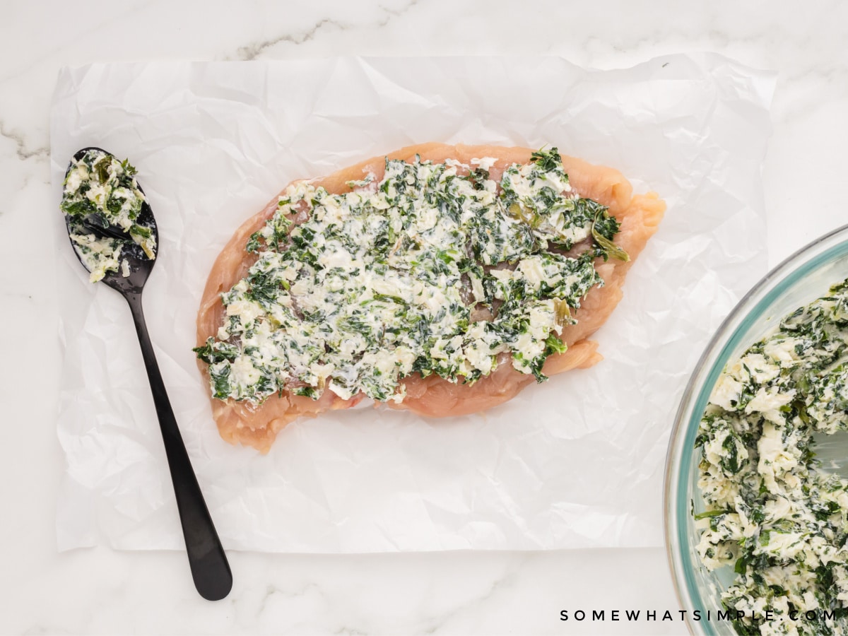 raw chicken breast with cream cheese and spinach mixture spread evenly on top