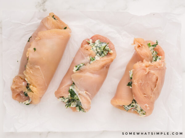 rolled raw chicken breasts with cream cheese and spinach in the center