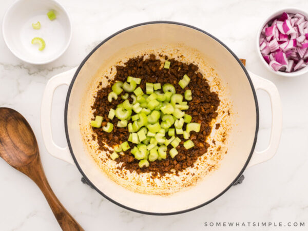 adding diced celery to chorizo in a pot