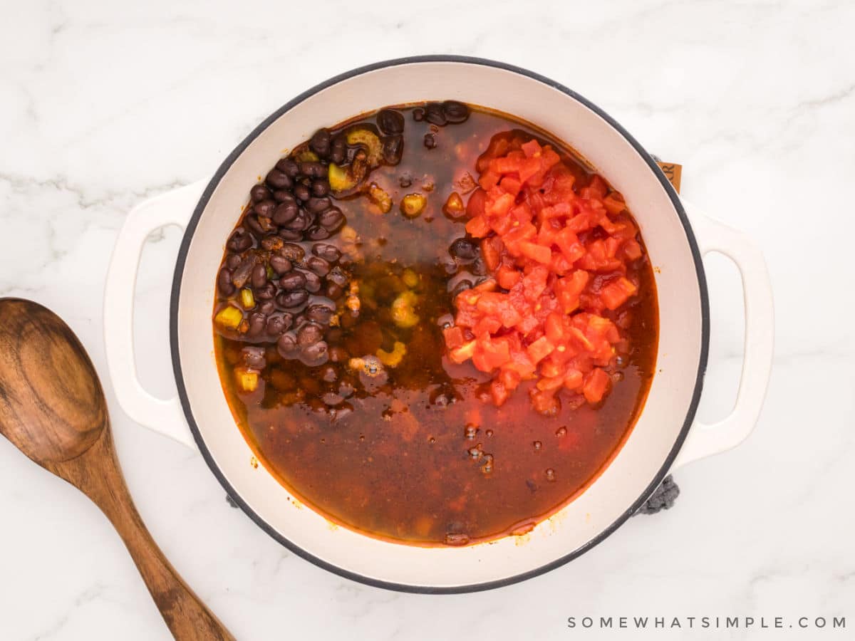 adding more ingredients to a pot of chorizo soup