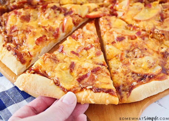 a pizza topped with bacon, cheddar cheese and apple slices