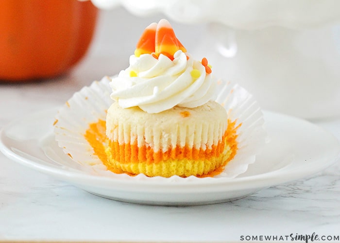 a Candy Corn Cupcake with orange, yellow and white layers on a plate topped with cream cheese frosting