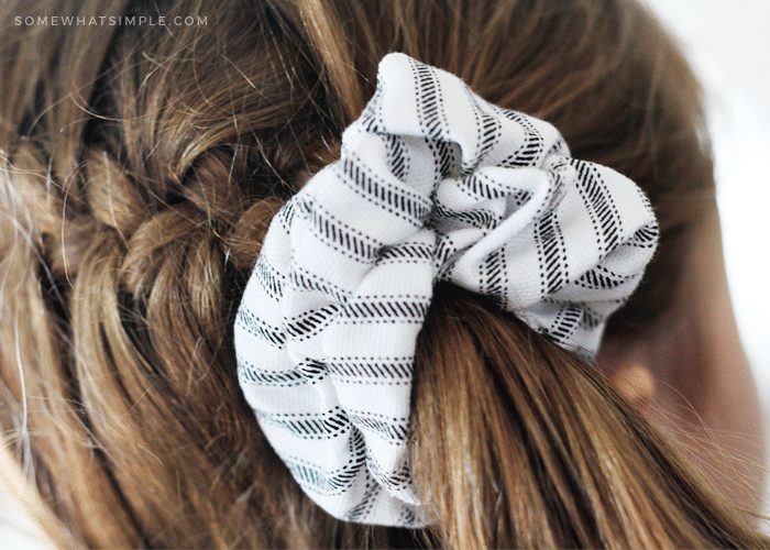 a white and grey striped scrunchie being worn in a pony tail by a young girl