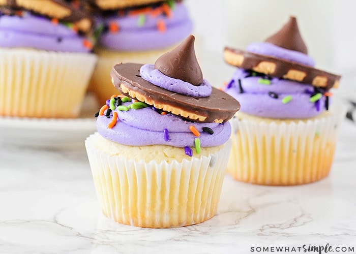 two Witch Hat Cupcakes on a counter with a tray filled behind them