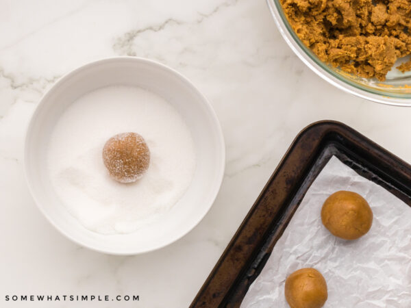 rolling cookie dough in a bowl of sugar