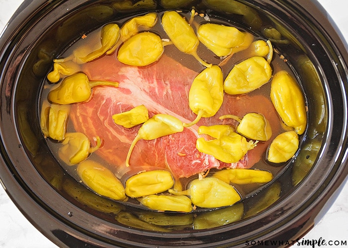 a crock pot with raw meat and pepperoncinis