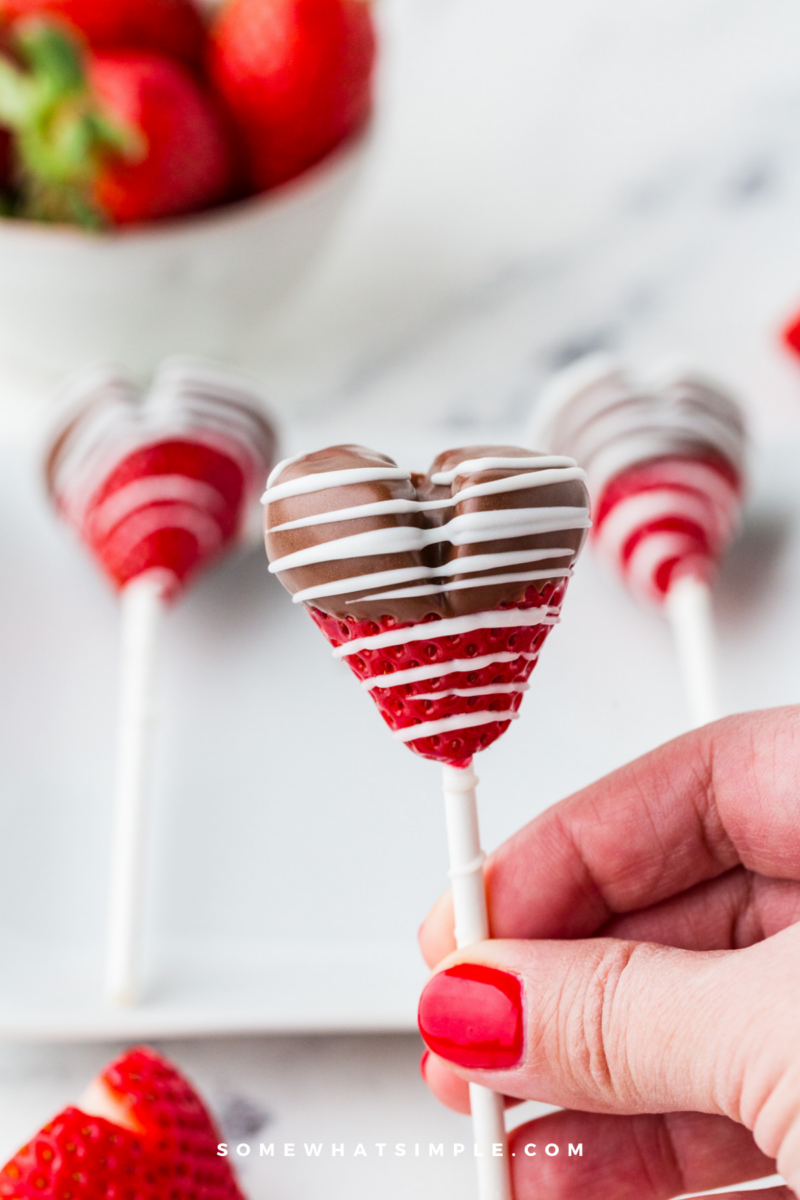 holding a chocolate strawberry heart pop