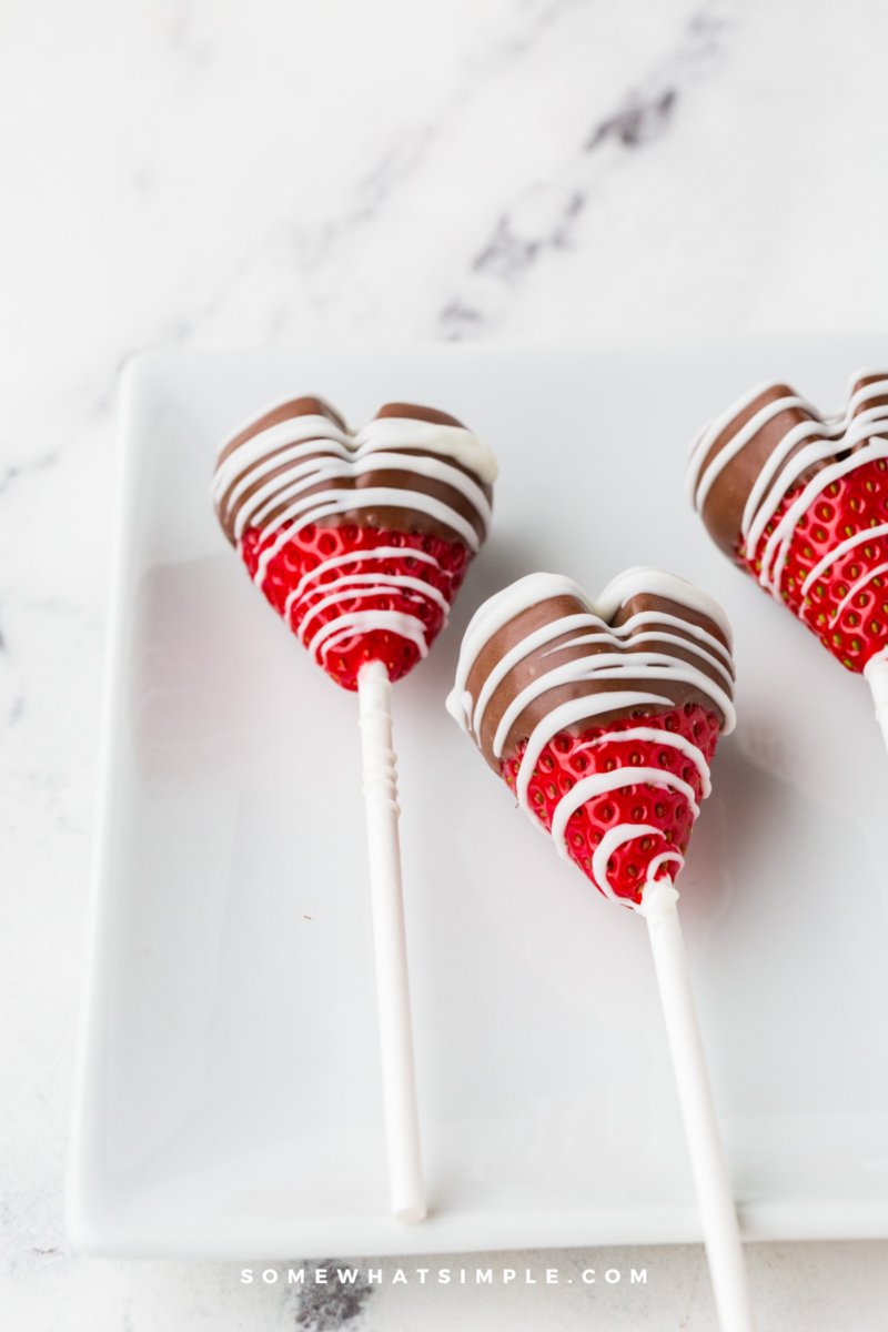 chocolate strawberry heart pops laying on a white counter