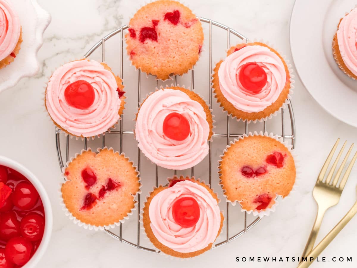 frosted cherry cupcakes on a wire baking rack