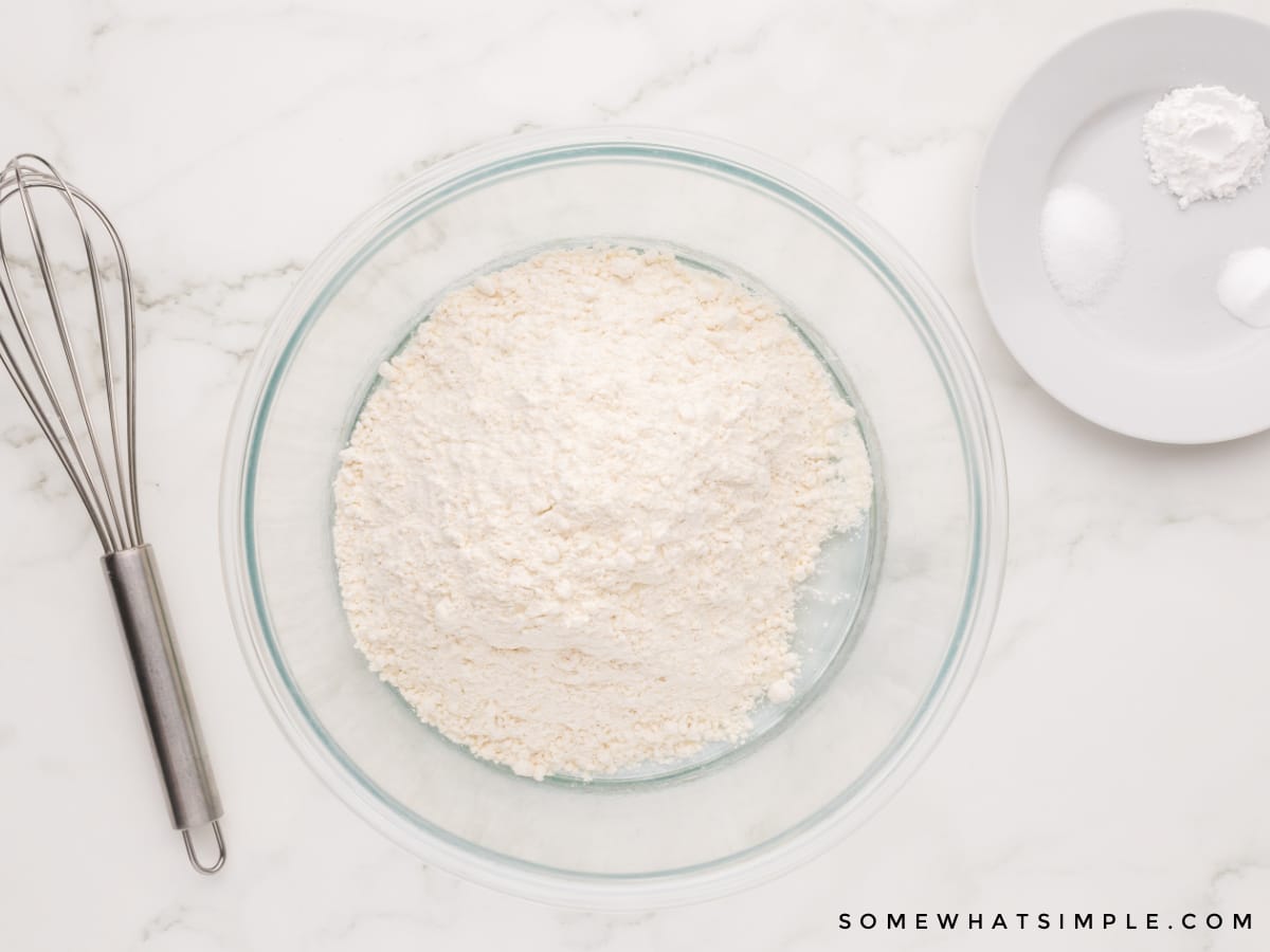 adding dry ingredients to a glass bowl