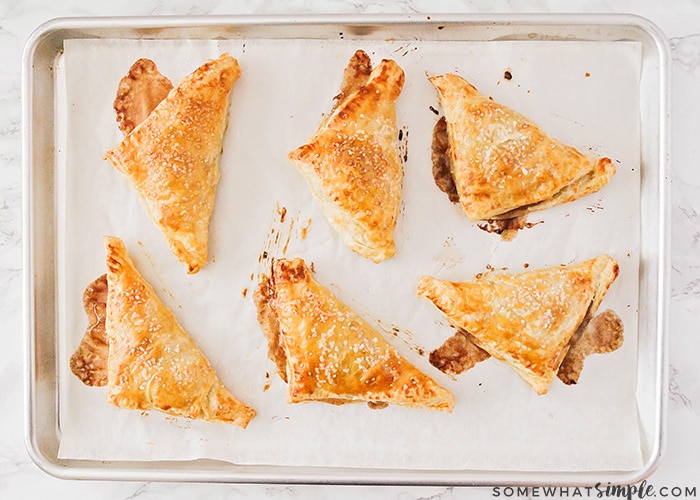 six baked apple turnovers made with puff pastry on a baking sheet made using this easy recipe